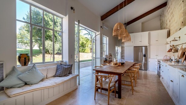 A spacious kitchen with a large island, white cabinetry, and a view of the outdoors.
