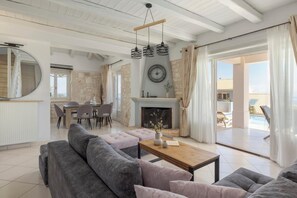 A spacious living area with a fireplace, a dining table with chairs, and a large window overlooking a pool.