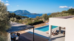 A modern villa with a swimming pool, outdoor seating, and a view of the sea and mountains. - Tina - Three Bedroom Villa, Sleeps 6 (Spartochori)