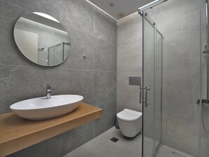 Bathroom features a large mirror, vessel sink, and glass-enclosed shower.