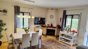 A living room with a fireplace, a dining table, chairs, a TV, and a sofa. - SAONA VILLAS (VN THAI): villa for 12 people, private pool, wifi (Les Tres Cales)