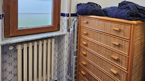 Une salle de bain avec un meuble en bois, un radiateur et une fenêtre donnant sur la mer.