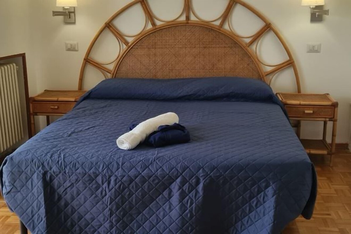 Uma cama com um edredom azul acolchoado e uma toalha enrolada.
