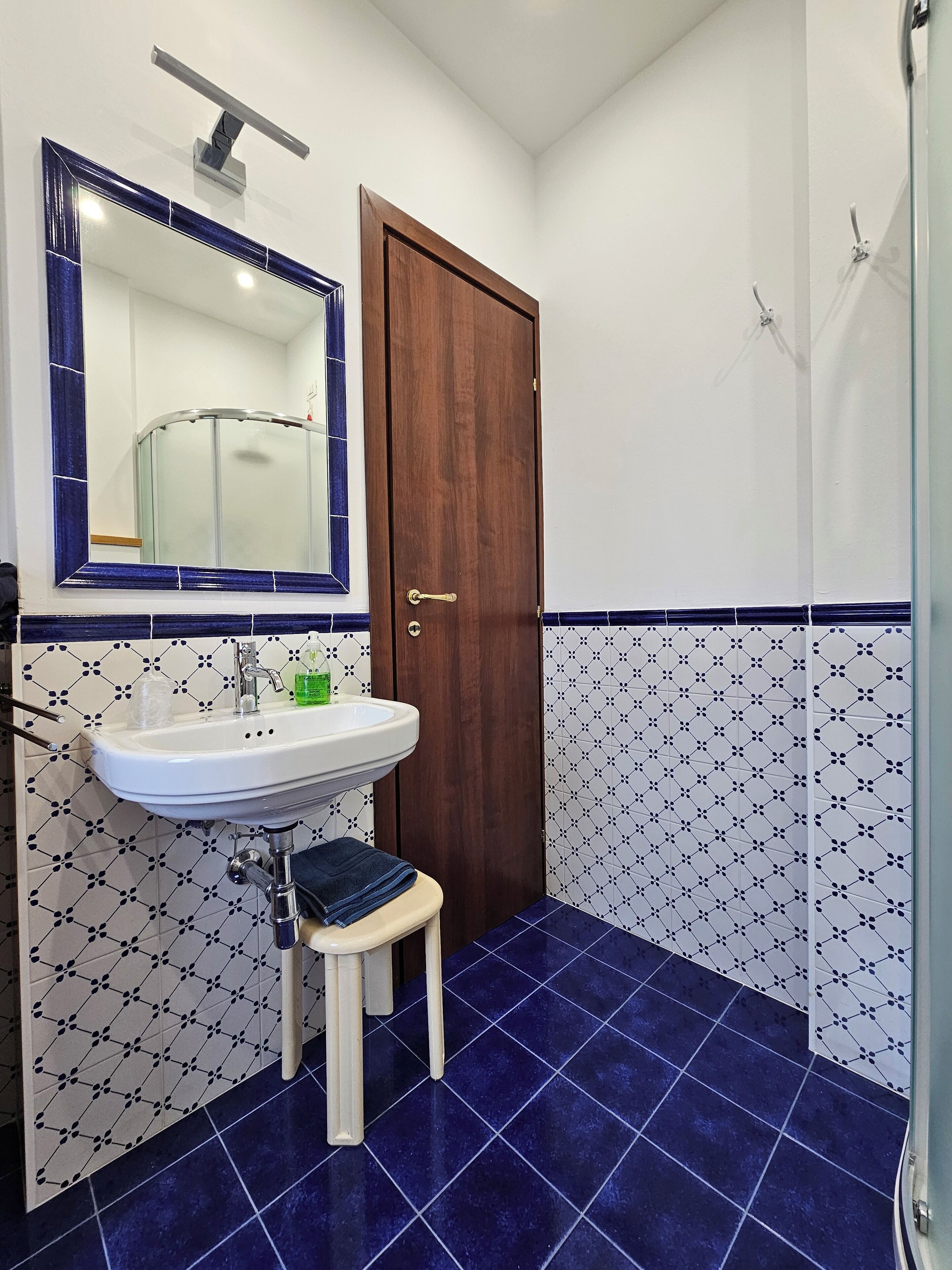 Une salle de bain avec un lavabo blanc, une porte en bois et un espace douche.
