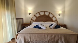 Un lit bien fait, avec une tête de lit, deux lampes de chevet et une table de chevet avec une lampe.
