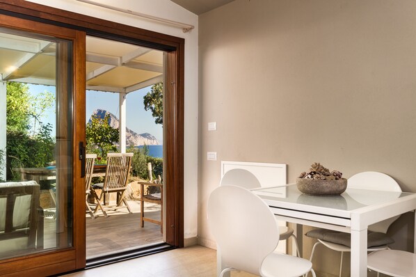 A modern dining area with a glass door leading to an outdoor patio. - Near the beach, Maìa panoramic suite for two people (Porto Taverna)
