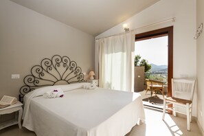A bedroom with a large bed, a chair, a small table with a lamp, and a view of the outdoors. - Near the beach, Maìa panoramic suite for two people (Porto Taverna)
