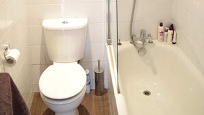 Uma casa de banho com sanita, chuveiro e banheira.