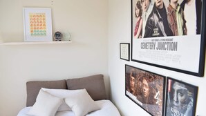 Quarto com cama, almofadas e uma parede decorada com posters de filmes.