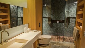 A modern bathroom with a large mirror, a white sink, a toilet, and a glass-enclosed shower area.