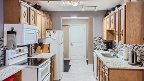 Une cuisine de taille réduite, avec des meubles de rangement en bois, un réfrigérateur blanc, un four à micro-ondes et une cuisinière.
