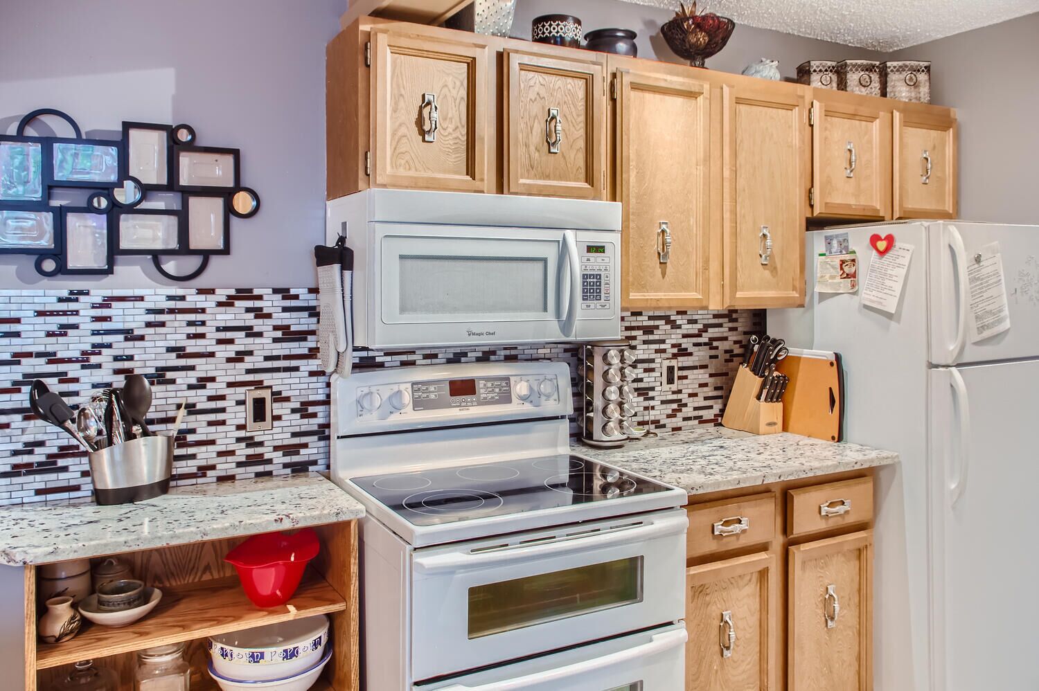 Una cocina con armarios de madera, un microondas, un horno y un refrigerador.