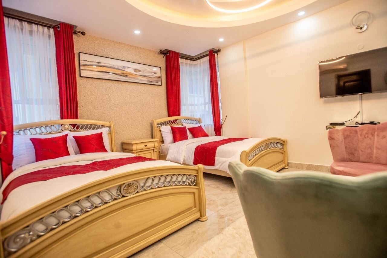 A hotel room with two beds, a TV, and a chair.