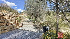 A stone pathway leading through a garden with potted plants and trees. - Maison Contemporaine Avec Piscine, vue Dégagée (Draguignan)
