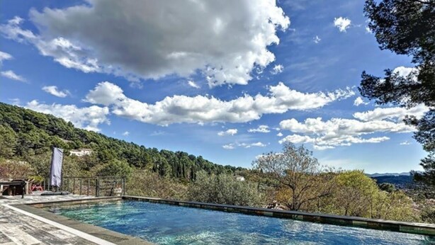 A swimming pool with clear water, surrounded by a wooden deck and a view of a forested hillside. - Maison Contemporaine Avec Piscine, vue Dégagée (Draguignan)