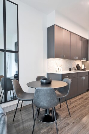Contemporary kitchen and dining area with a minimalist design, featuring a round table and two chairs.
