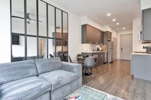 Relax in a spacious living area with a sofa, coffee table, and dining space, featuring a modern kitchen with a refrigerator and microwave.