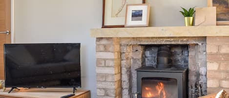 Ein Wohnzimmer mit Fernseher, Kamin und Steinwand.