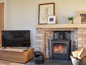 Una sala de estar con televisor, chimenea y pared de piedra.