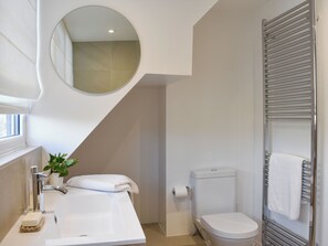 Un baño moderno con un lavamanos blanco, un inodoro, un perchero para toallas y un espejo.