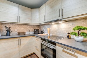 Een moderne keuken met lichte houtkleurige kastjes, een zwart aanrecht en een inbouwoven.