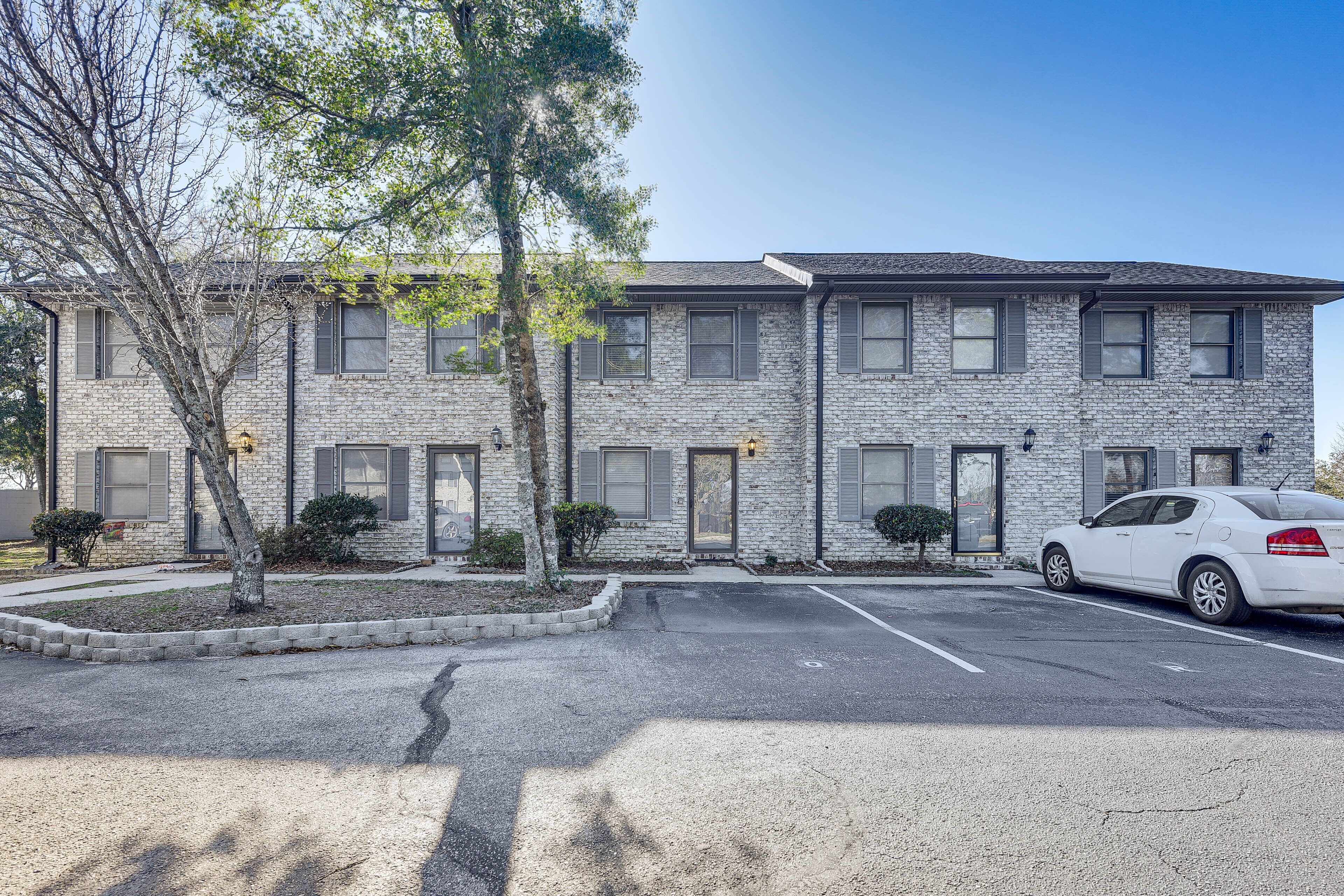 A two-story building with a parking lot and a white car parked in front.
