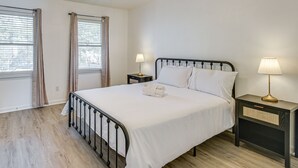 Ein ordentlich bezogenes Bett mit weißen Leinen, ein Nachttisch mit Lampe und ein Deckenventilator.