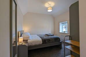 A bedroom with a bed, bedside lamp, window, radiator, and a mirror. - 1 Bed Adore Cottage - Bwthyn Bach Addawol (Holywell)