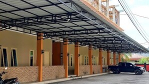 Un edificio con estacionamiento techado, una motocicleta y una camioneta pickup.