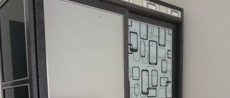 A room with a large window, a mirror, and a patterned wall.