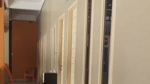 Un pasillo con puertas que dan a varias habitaciones, un bote de basura y una silla.