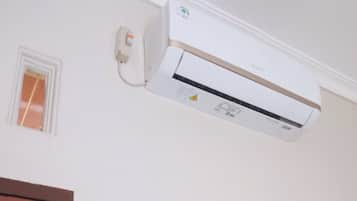 A white air conditioning unit mounted on a wall with a small window to its left.