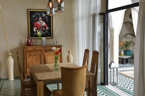 A dining area with a table, chairs, and a vase of flowers. - Riad Palau Marrakech (Marrakech)