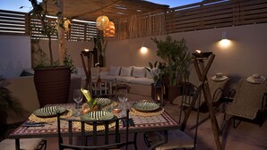 An outdoor dining area with a table set for four, surrounded by wicker chairs and a cushioned sofa. - Riad Palau Marrakech (Marrakech)