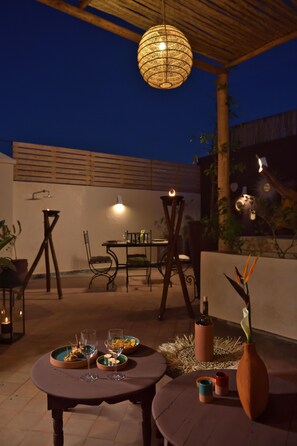 An outdoor patio with a round table, chairs, and a hanging light fixture. - Riad Palau Marrakech (Marrakech)