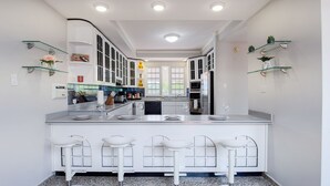 A modern kitchen with white cabinetry, a central island with bar stools, and built-in appliances.
