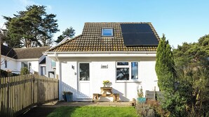 A single-story house with a tiled roof, a small window, and a solar panel.