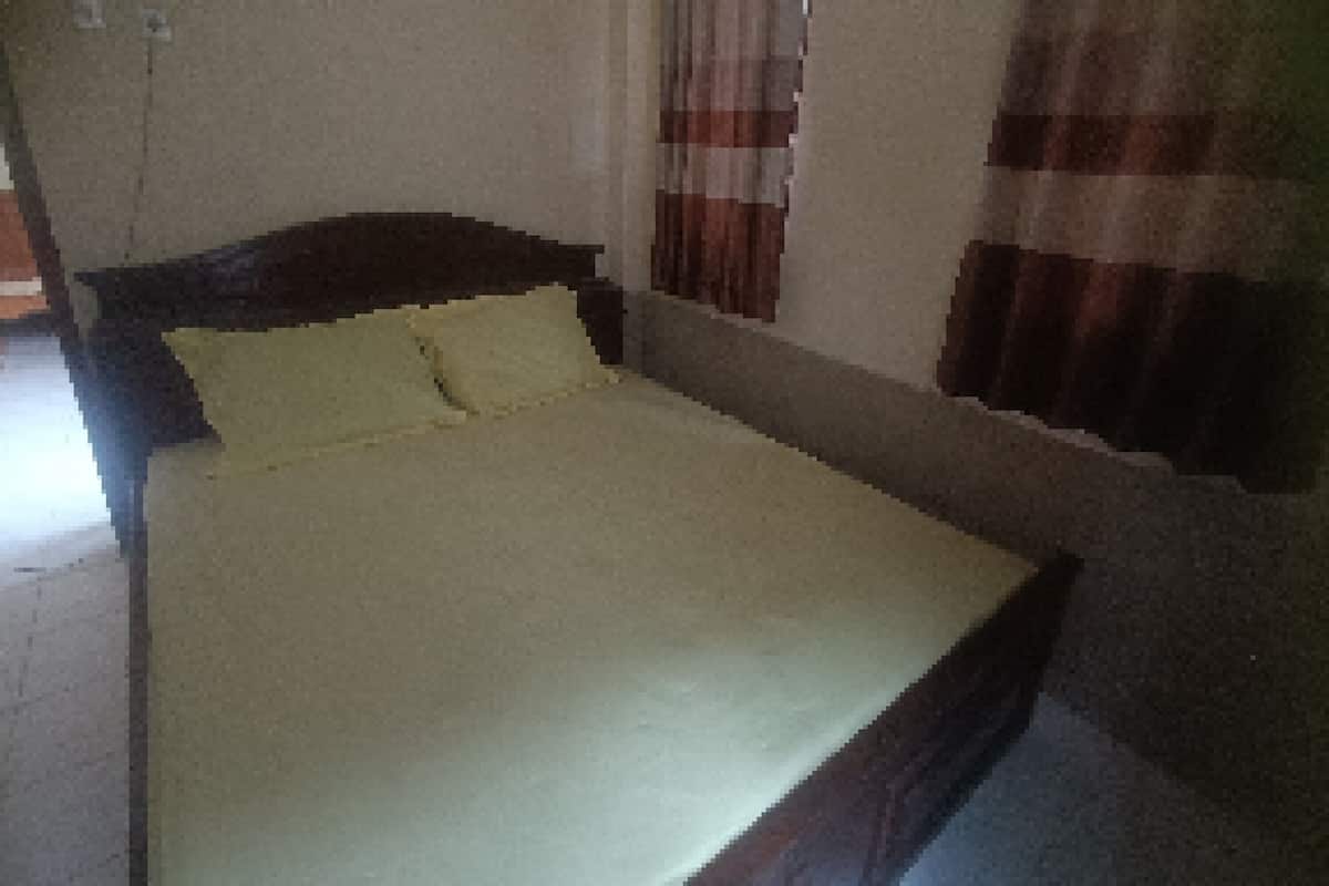 A small, single-bed room with a plain bedspread and a headboard.