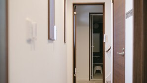 A narrow hallway with a wooden door on the right and a closet with a toilet visible in the background.