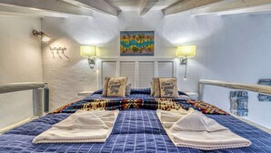Un dormitorio con una cama, dos lámparas de pared, un cuadro y una ventana con persianas.