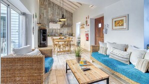 Amplia sala de estar con muebles de mimbre, una mesa de centro de madera y vistas a la cocina.