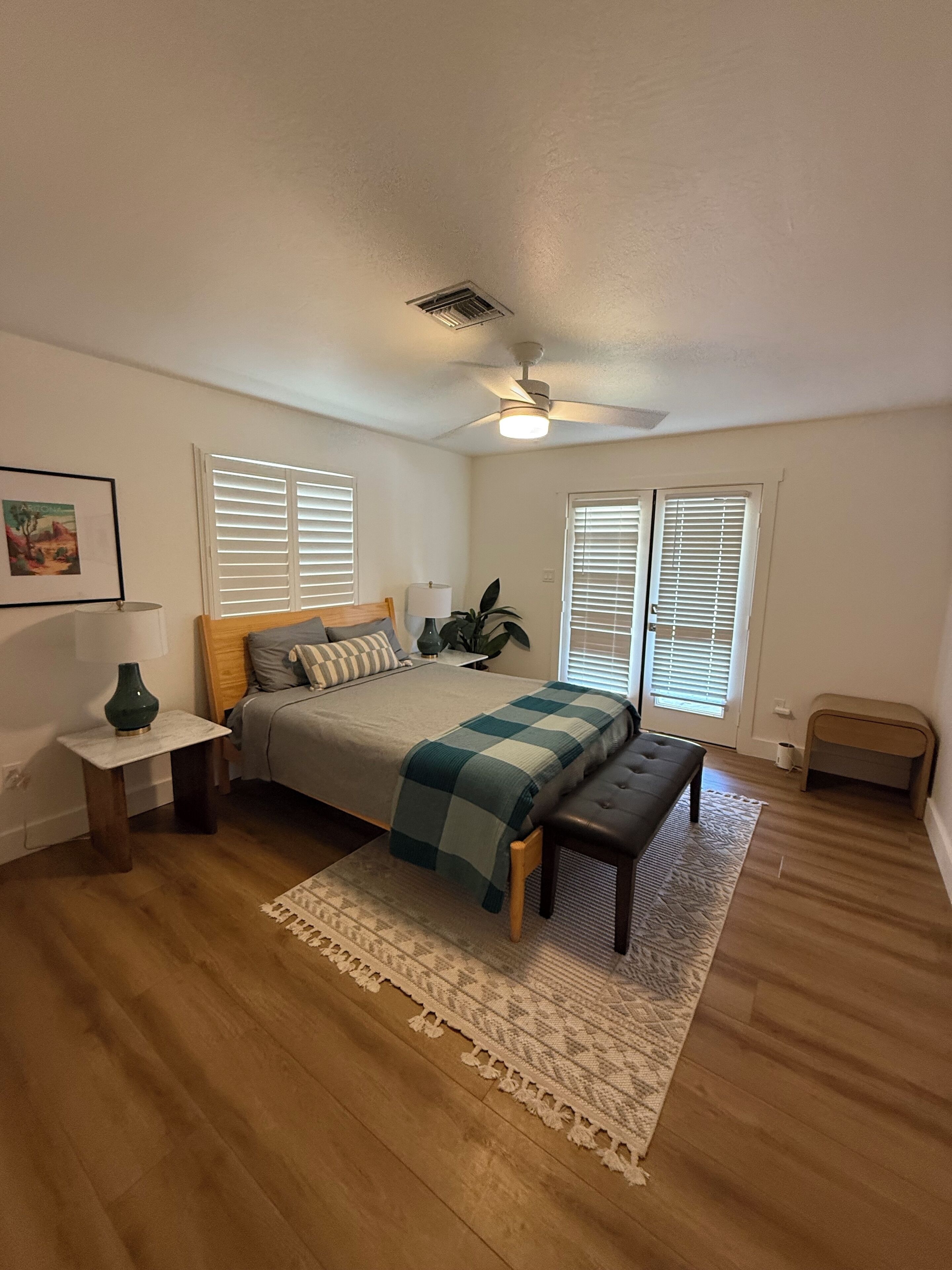 Une chambre à coucher avec un lit, une table de chevet, une lampe et un ventilateur de plafond.