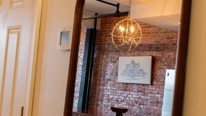 A room with a brick wall, a hanging light fixture, and a framed picture. - Luxurious 2 BR Loft  (Utica)