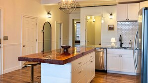 A kitchen with a marble countertop, stainless steel appliances, and a central island with bar stools. - Luxurious 2 BR Loft  (Utica)