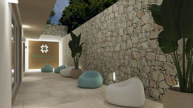 Un pasillo con pared de piedra, un cartel que dice 'MARGAIDA BOUTIQUE HOTEL SPA' y varios pufs.