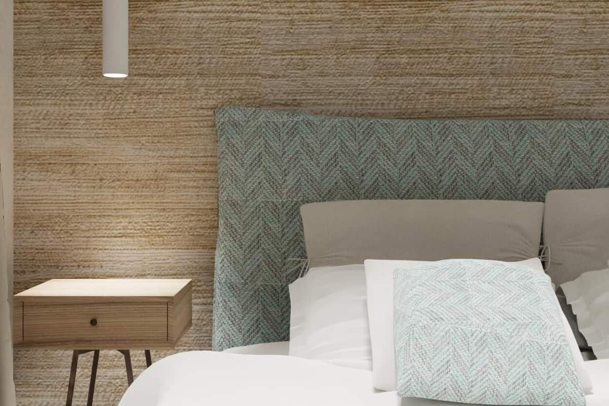 Une chambre à coucher moderne avec une tête de lit à motifs en chevrons, une table de chevet et un luminaire suspendu.