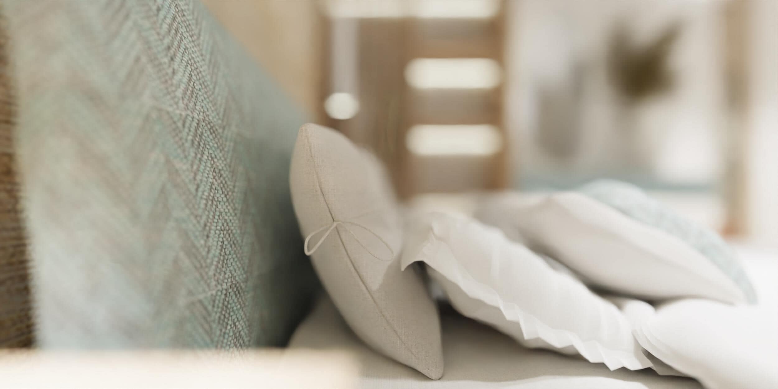 A close-up of a bed with a white pillow and a folded white pillow on a textured fabric.