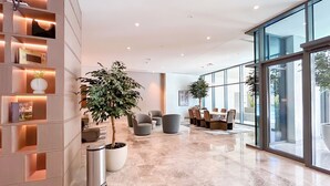 A modern lobby with a marble floor, seating area, and large windows.