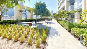 A modern outdoor corridor with benches, greenery, and a clear view of the city skyline.