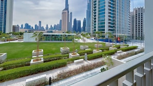 Un paisaje urbano moderno con rascacielos, un espacio verde cuidado con jardineras, y una vista despejada del horizonte de la ciudad.